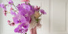 Turntable showcasing a realistic artificial flower bridal bouquet featuring purple artificial orchids, pink artificial cosmos, champagne artificial tea roses, blush artificial peonies, white artificial hydrangeas, mauve artificial dahlias, and pink artificial tulips — from My Faux Florist Canada.