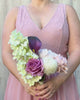 Alt text: Bridesmaid holding a realistic artificial flower bouquet featuring pale green artificial hydrangeas, mauve artificial roses, blush artificial peonies, white artificial allium, and deep wine artificial calla lilies — from My Faux Florist Canada.