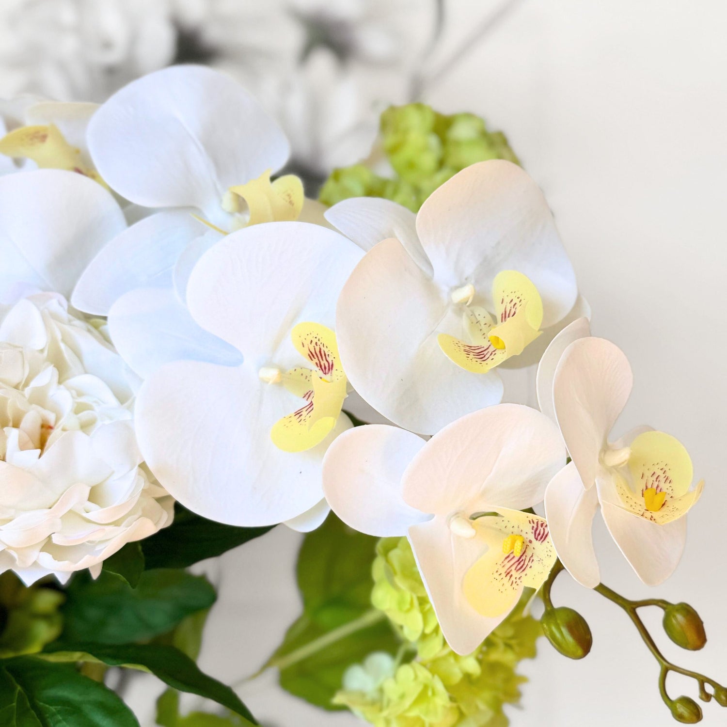 Close-up of white and yellow realistic artificial orchids with green leaves - for My Faux Florist Canada.
