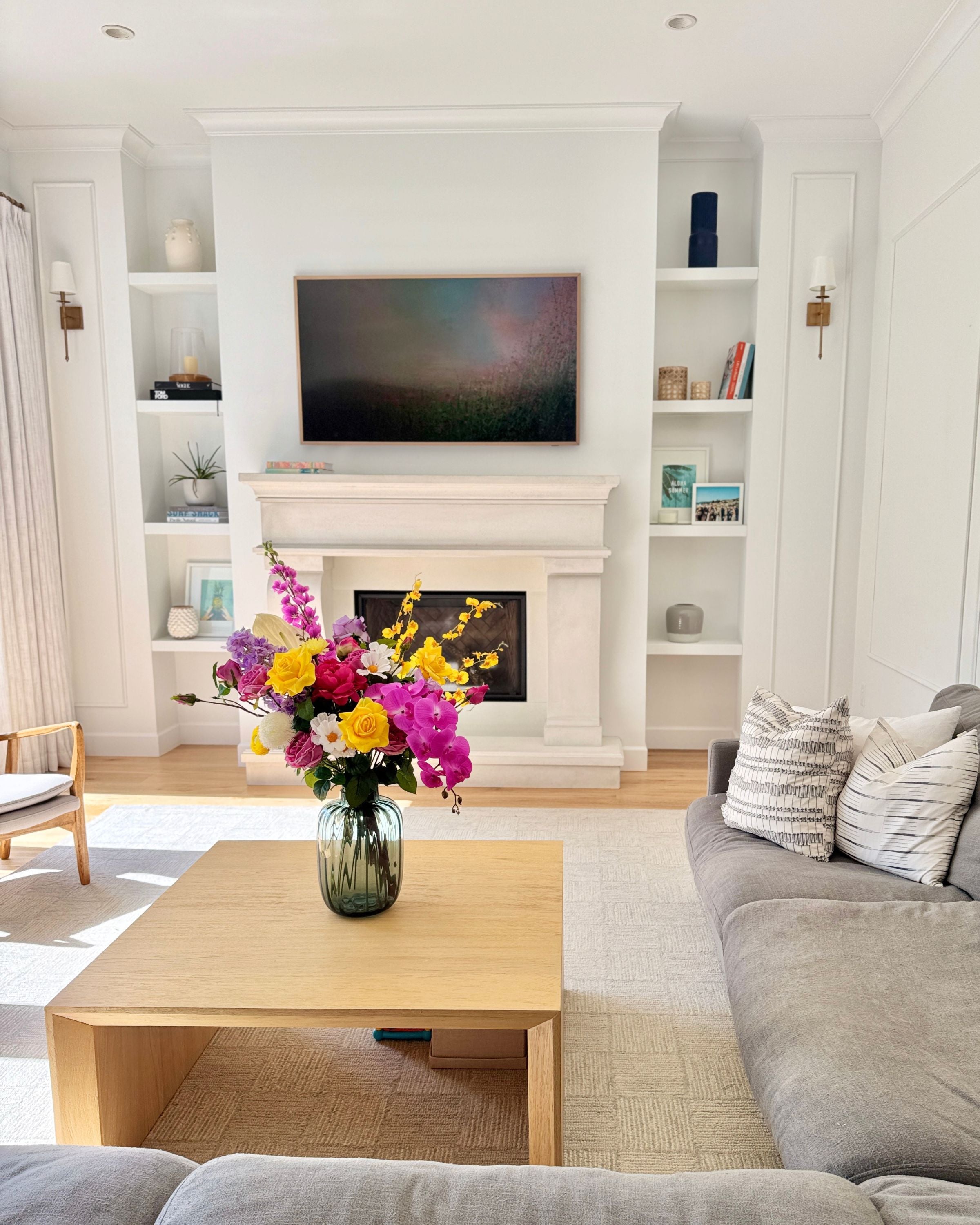 Living room with a coffee table, gray sofa, and colorful realistic artificial flowers in a vase. Faux peonies, faux roses, faux hydrangea, and faux orchids in an artificial flower bouquet for My Faux Florist Canada.