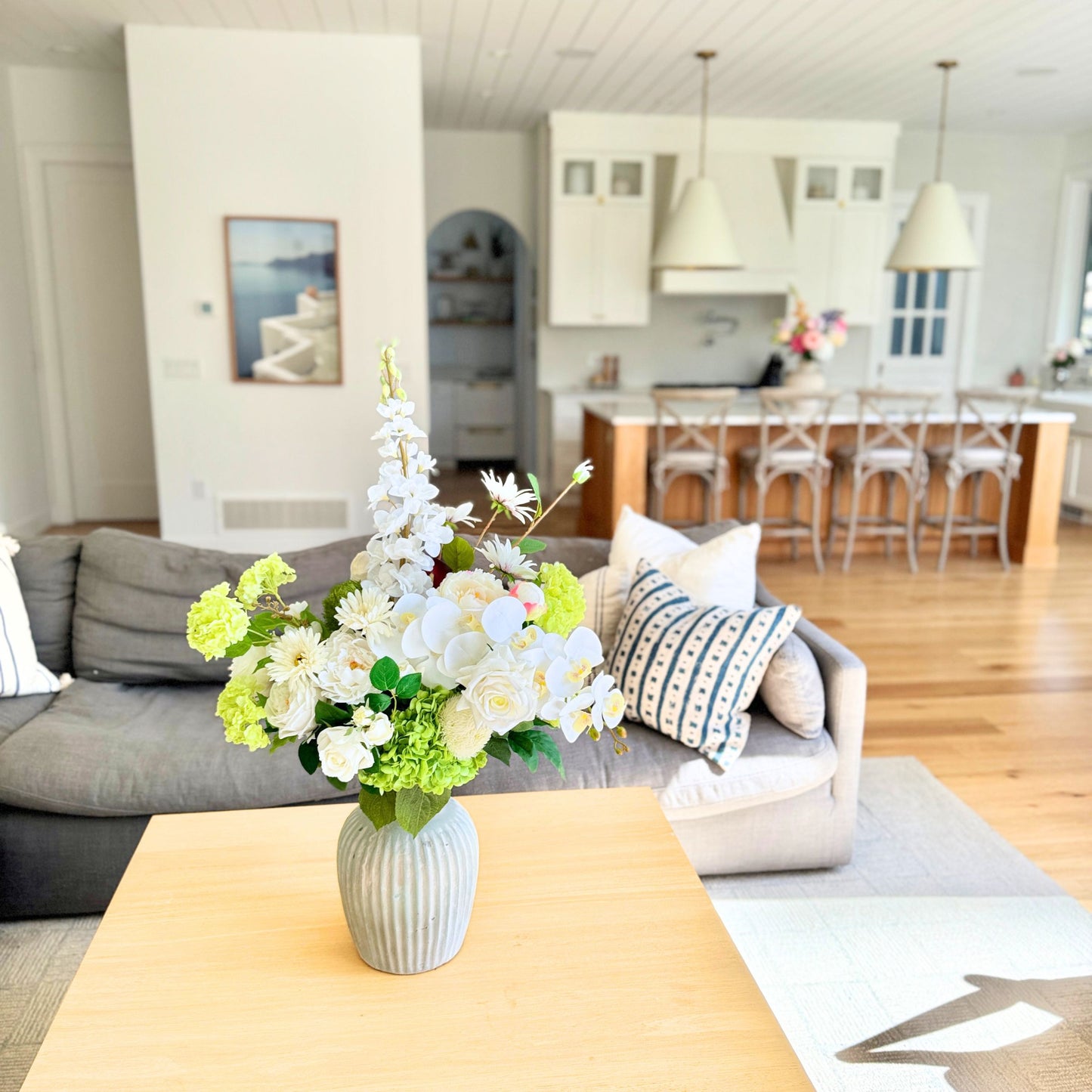Living room with a vase of realistic artificial flowers on a coffee table, leading to a kitchen. Faux peonies, faux roses, faux hydrangea, and faux orchids in an artificial flower bouquet for My Faux Florist Canada.