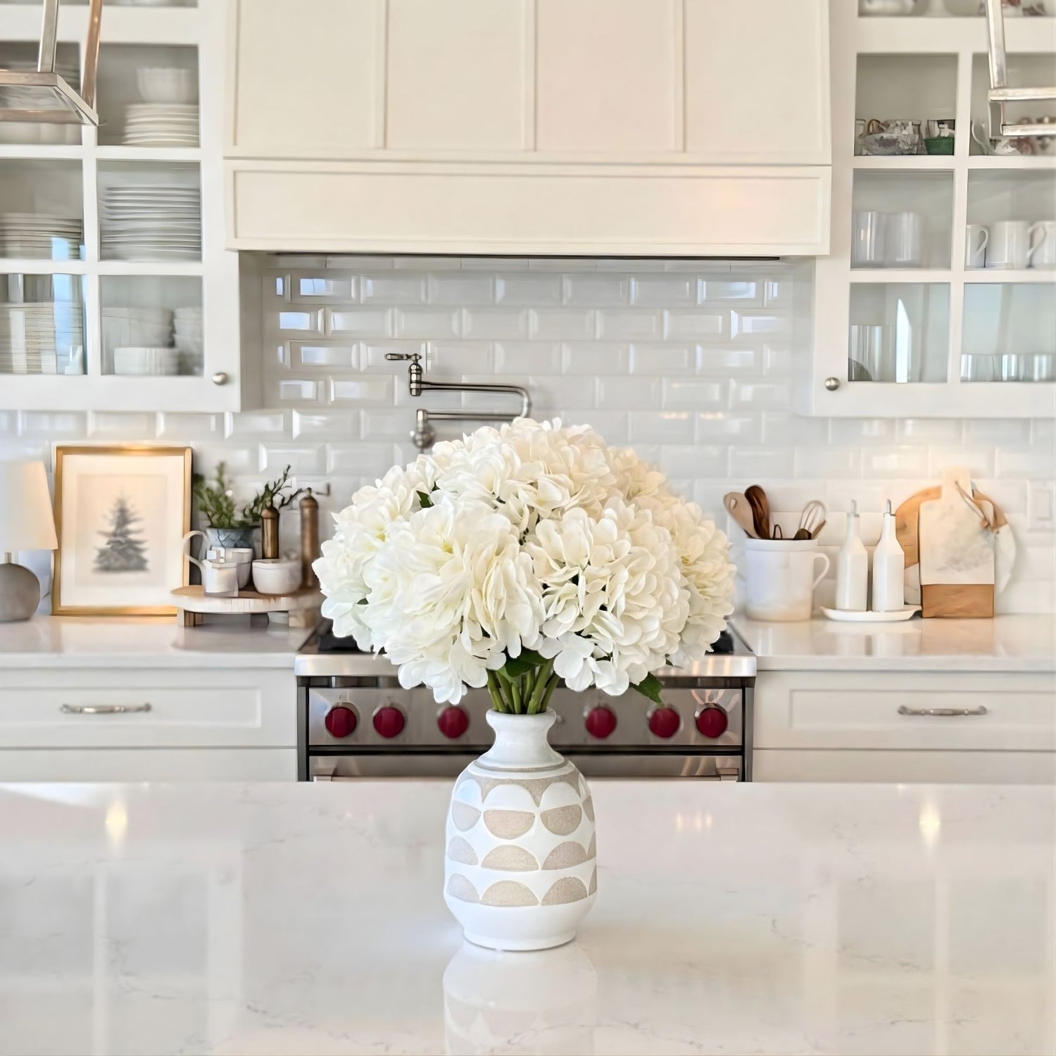 White, realistic artificial hydrangeas in a vase on a kitchen counter with white cabinets and backsplash- for My Faux Florist Canada.