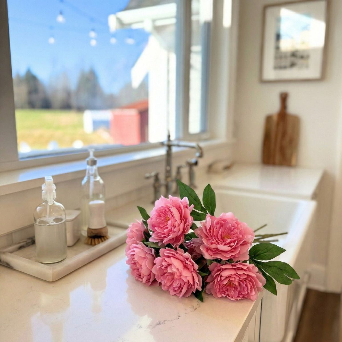 Pink realistic artificial peonies on a kitchen counter with a window view. realistic artificial peonies from My Faux Florist Canada.