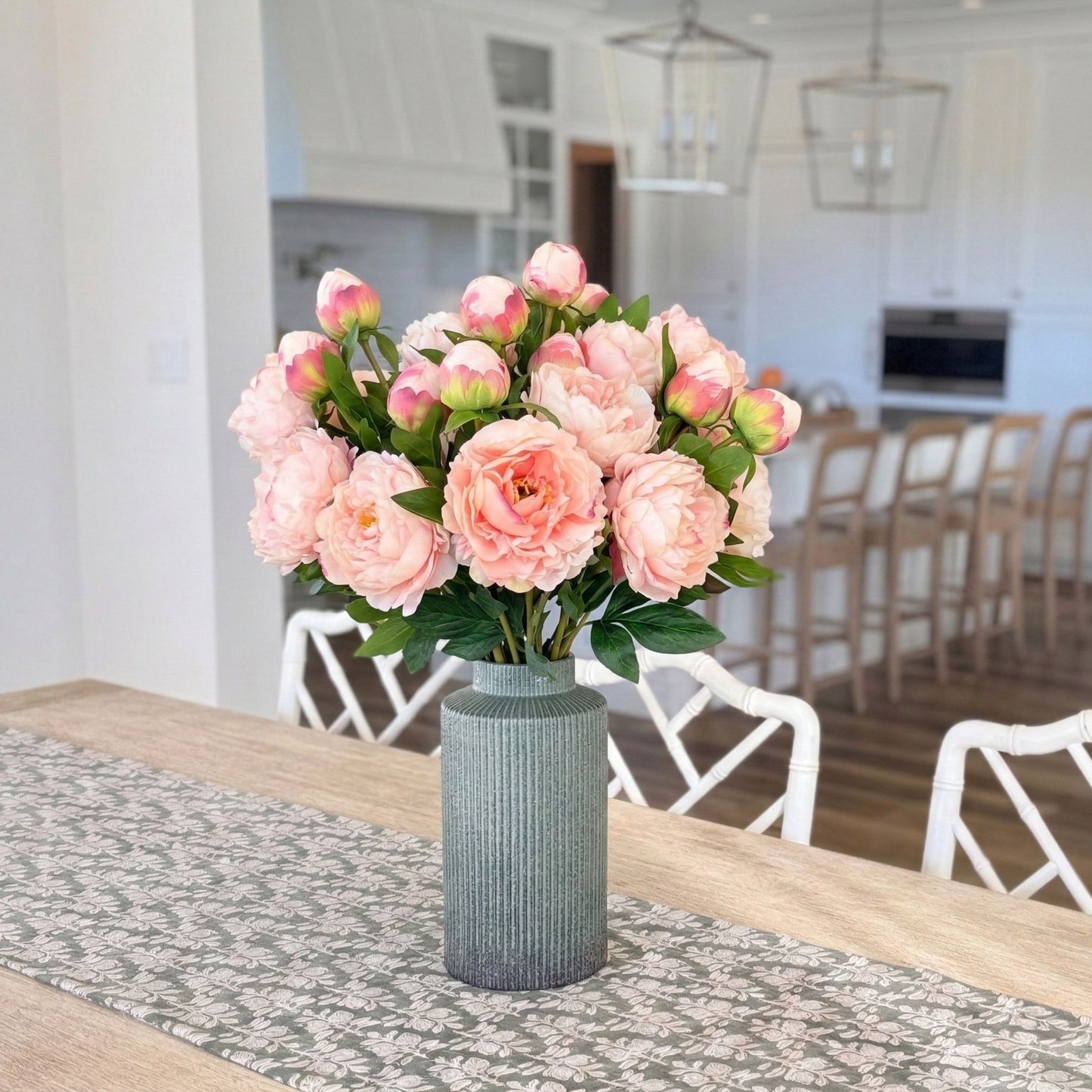 green vase full of realistic artificial peonies in pink, with kitchen in the background for My Faux Florist Canada