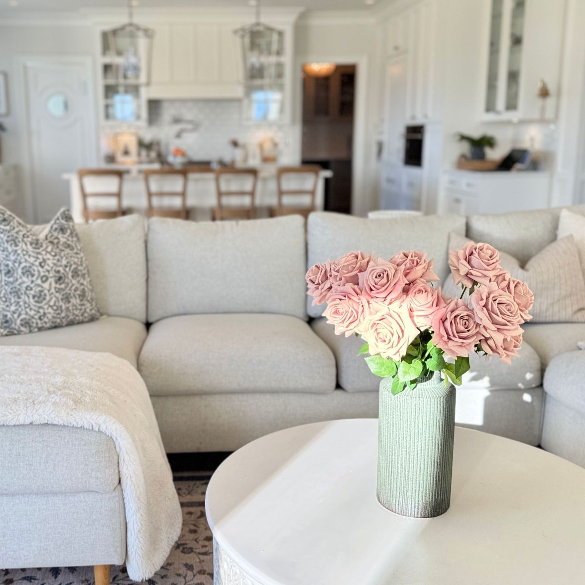 Floral arrangement of pink realistic artificial roses in a living room with a couch and coffee table - for My Faux Florist Canada.