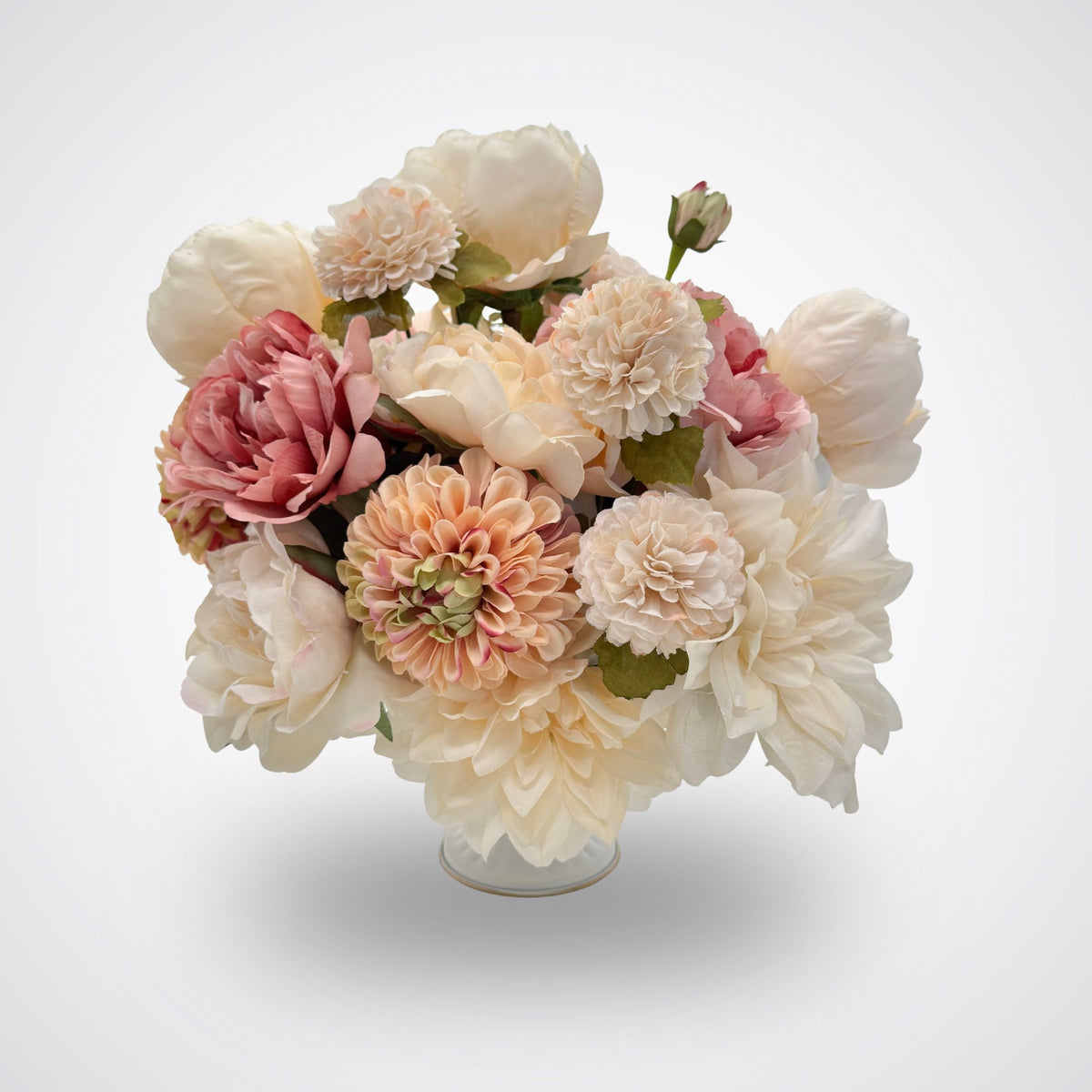 A bouquet of artificial flowers in a clear glass vase, featuring cream, blush pink, and peach blooms with green foliage, set against a light gray background. A realistic artificial flower arrangement for Fall. Artificial flowers from My Faux Florist Canada.