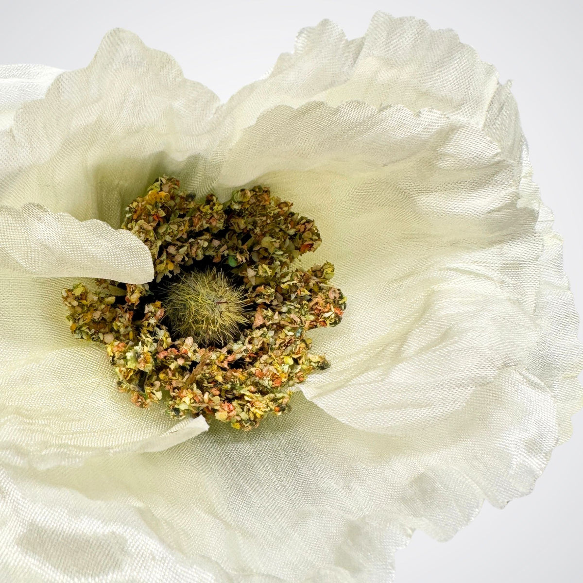 A close-up of a white silk poppy  artificial flower with a textured, dried-looking center, photographed against a plain white background. For My Faux Florist Canada.