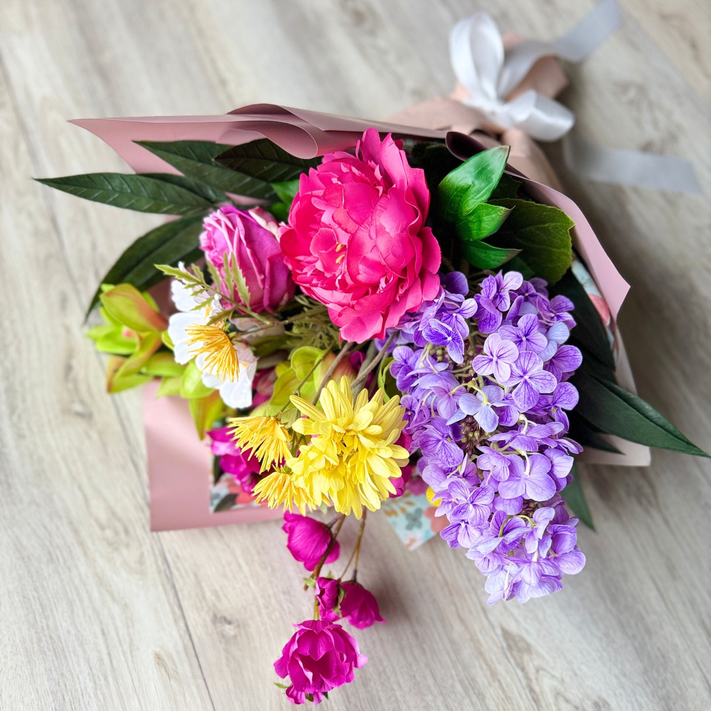 Bouquet of colorful artificial flowers held by a person against a neutral background - bouquets includes artificial orchids artificial roses, artificial peonies, real touch flowers from my faux florist canada