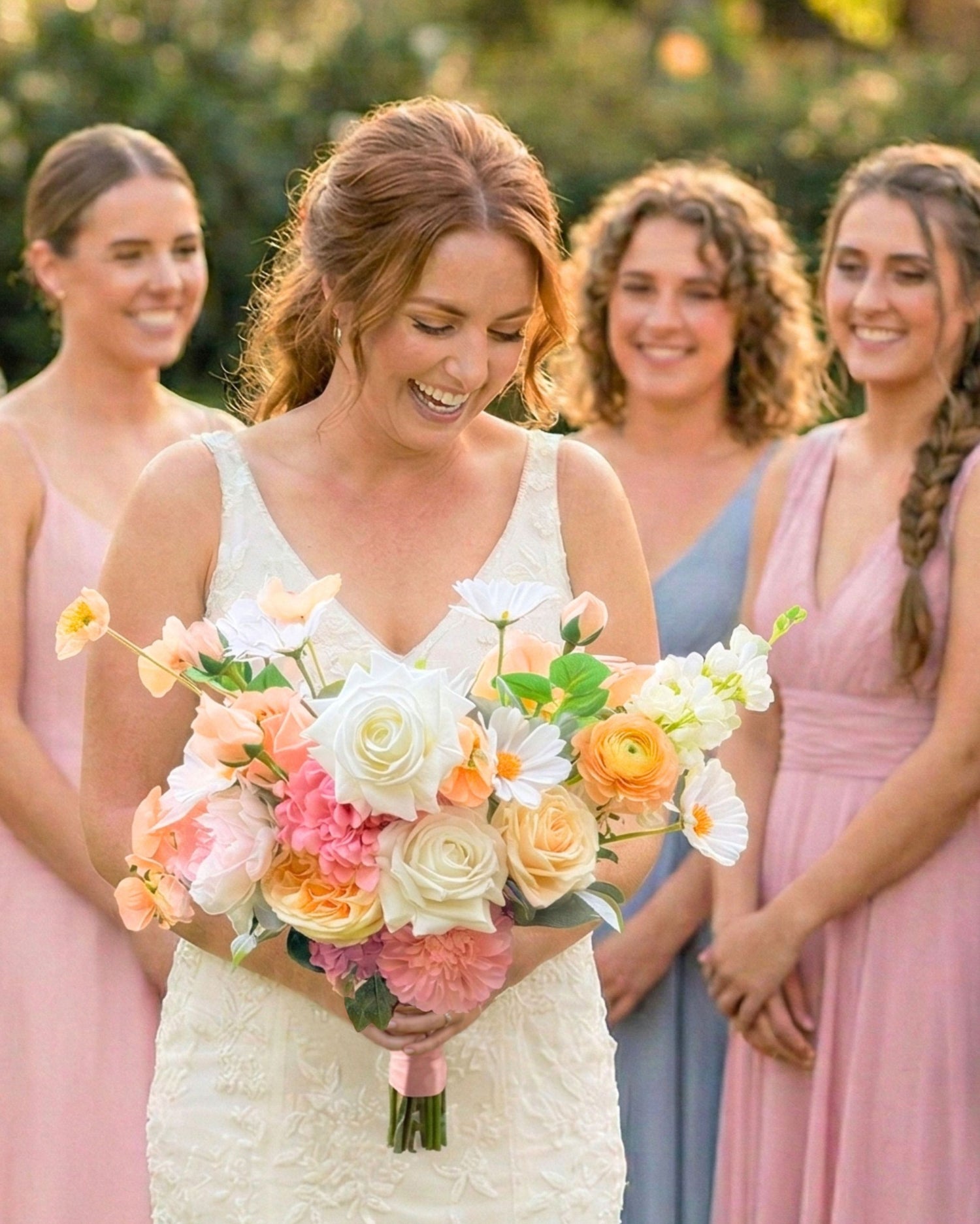 Bride standing outdoors holding an artificial wedding bouquet of realistic artificial flowers in peaches, whites and pinks from My Faux Florist Canada.