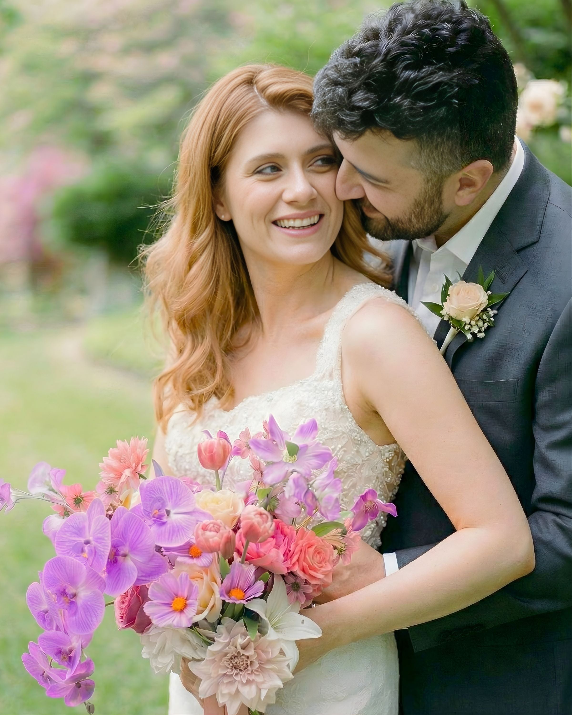 Bride and groom standing outdoors holding an artificial wedding bouquet of realistic artificial flowers in peaches, whites and pinks from My Faux Florist Canada.