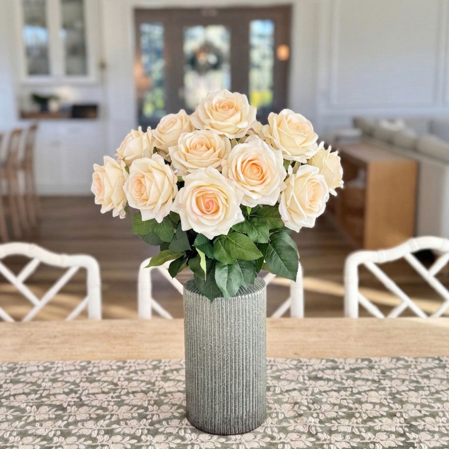 Bouquet of white and cream realistic artificial roses in a textured vase on a table with a blurred indoor background, from My Faux Florist Canada