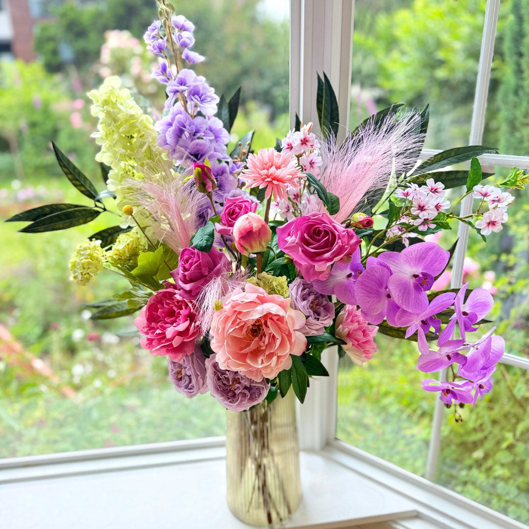 Bouquet of brightly coloured artificial flowers and Real Touch flowers in a window, by My Faux Florist artificial flowers Canada.